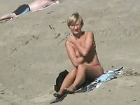 Lovely blonde milf half naked sun bathing on the beach