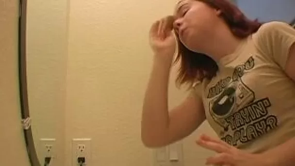 Redhead teen babe in the bathroom putting her makeup on