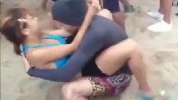 A slutty girl rubs her butt against a guy's groin on a beach