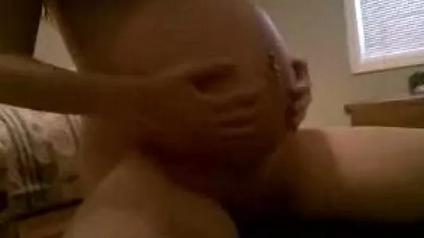 My nine months pregnant wife rubs her big belly in the bedroom