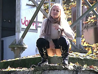 Blonde chick climbs on the concrete wall and urinates