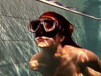 Hot redhead babe in the diver mask swimming under water