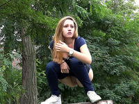 Sporty blonde sweetie sits on the tree stub and pees