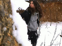 Brunette hot young chick walks in the winter forest and pisses behind the rock