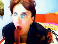 Four eyed mature whore is sucking her big dildo like a woman possessed