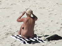 Topless blonde MILF in sunglasses flashed her nice bum on the beach