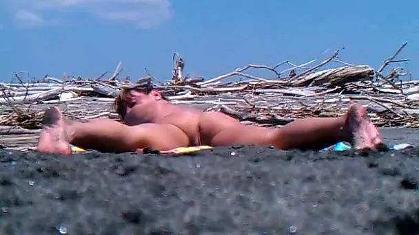 Booty girl is posing in doggy style position on a nude beach