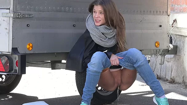 Skinny young hottie hides behind the trailer and pisses