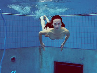 Sweet and skinny brunette teen in blue bikini dives in the pool