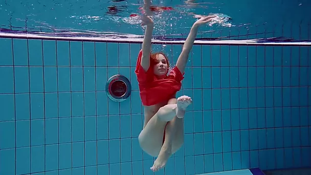 Slender and cute redhead white girl dives in the pool and undresses underwater
